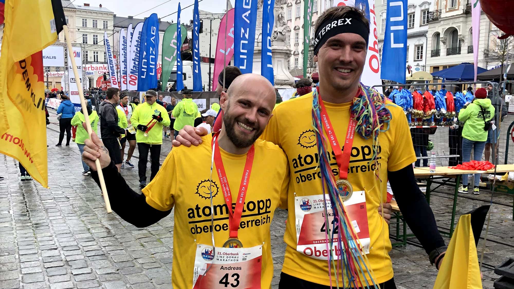 2 atomstopp Läufer mit gelben Laufshirts und Fahnen beim Linz Marathon